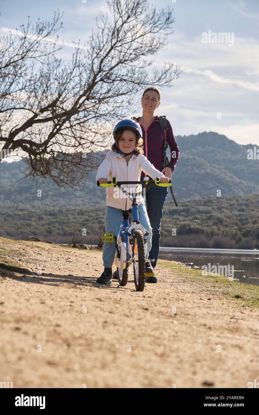 A mother watching her son ride a bicycle Stock Photo - Alamy