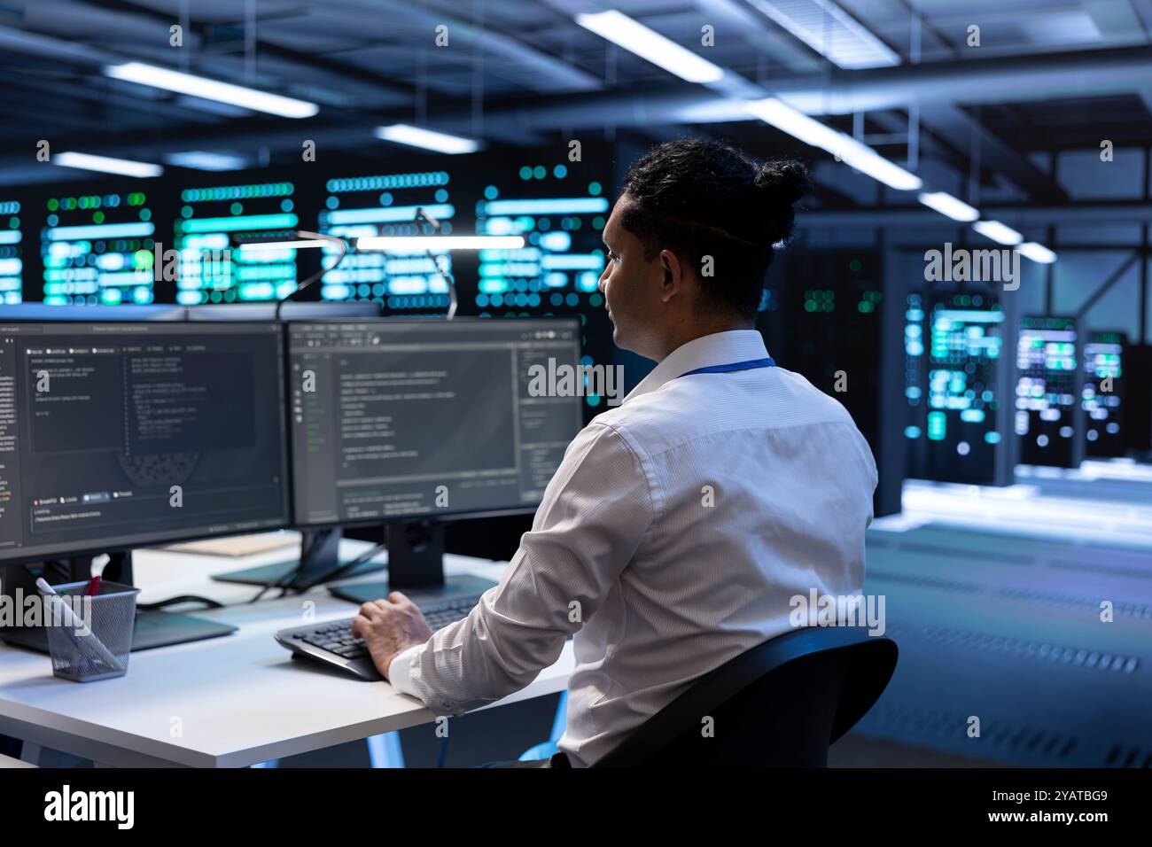 Admin in data center updating systems to keeps performance up and protect servers from easily exploitable software vulnerabilities. Worker looking for errors causing servers to slow down Stock Photo
