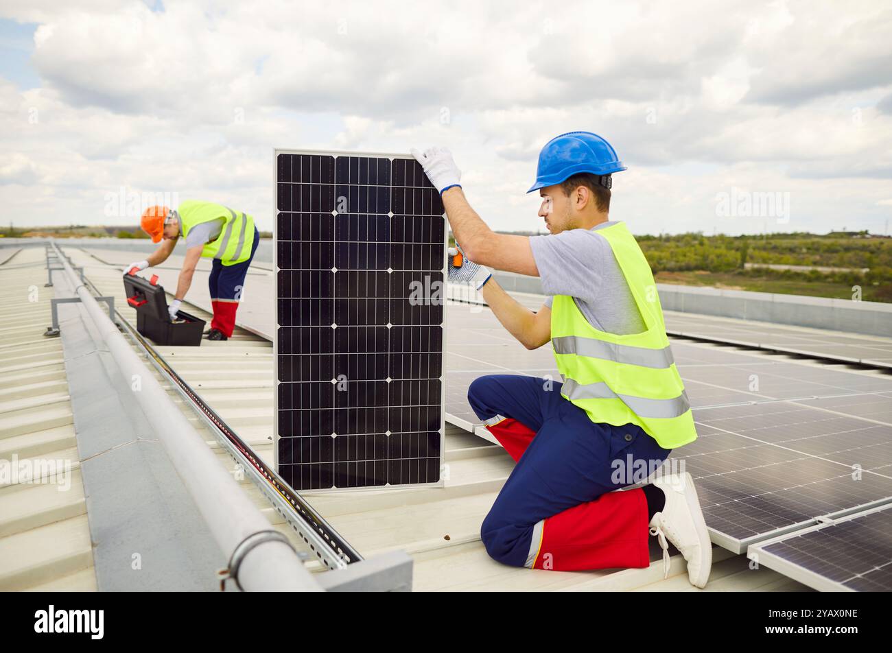 Electrician On Roof Installing Or Maintaining Solar Panels Stock Photo
