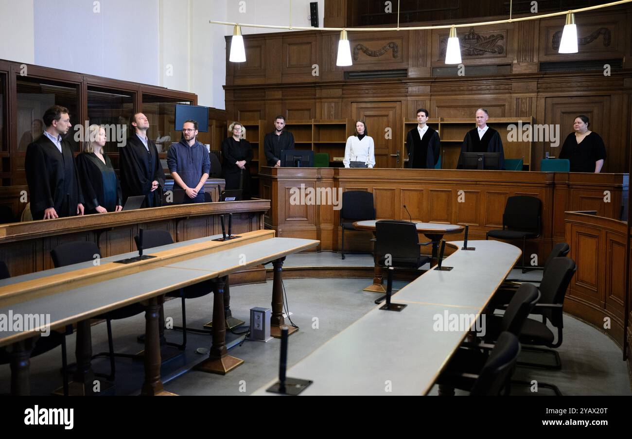 16 October 2024, Berlin: Arne Semsrott (4th from left), editor-in-chief of the internet portal "FragdenStaat", stands with his lawyers Benjamin Lück (l-r), Hannah Vos and Lukas Theune in the hearing room at Berlin District Court at the start of a trial against him. Presiding judge Bo Meyer (2nd from right) stands in the middle of the courtroom. The prosecution accuses the journalist of publishing court orders without permission. In August 2023, the journalist allegedly published search warrants from an ongoing investigation against the climate group Letzte Generation, some of which were blacke Stock Photo