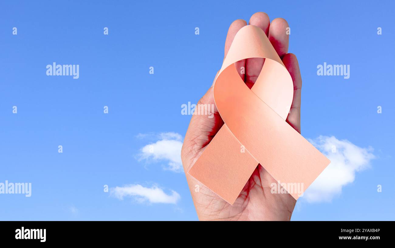 Hand holding peach ribbon, symbolizing uterine cancer awareness ...