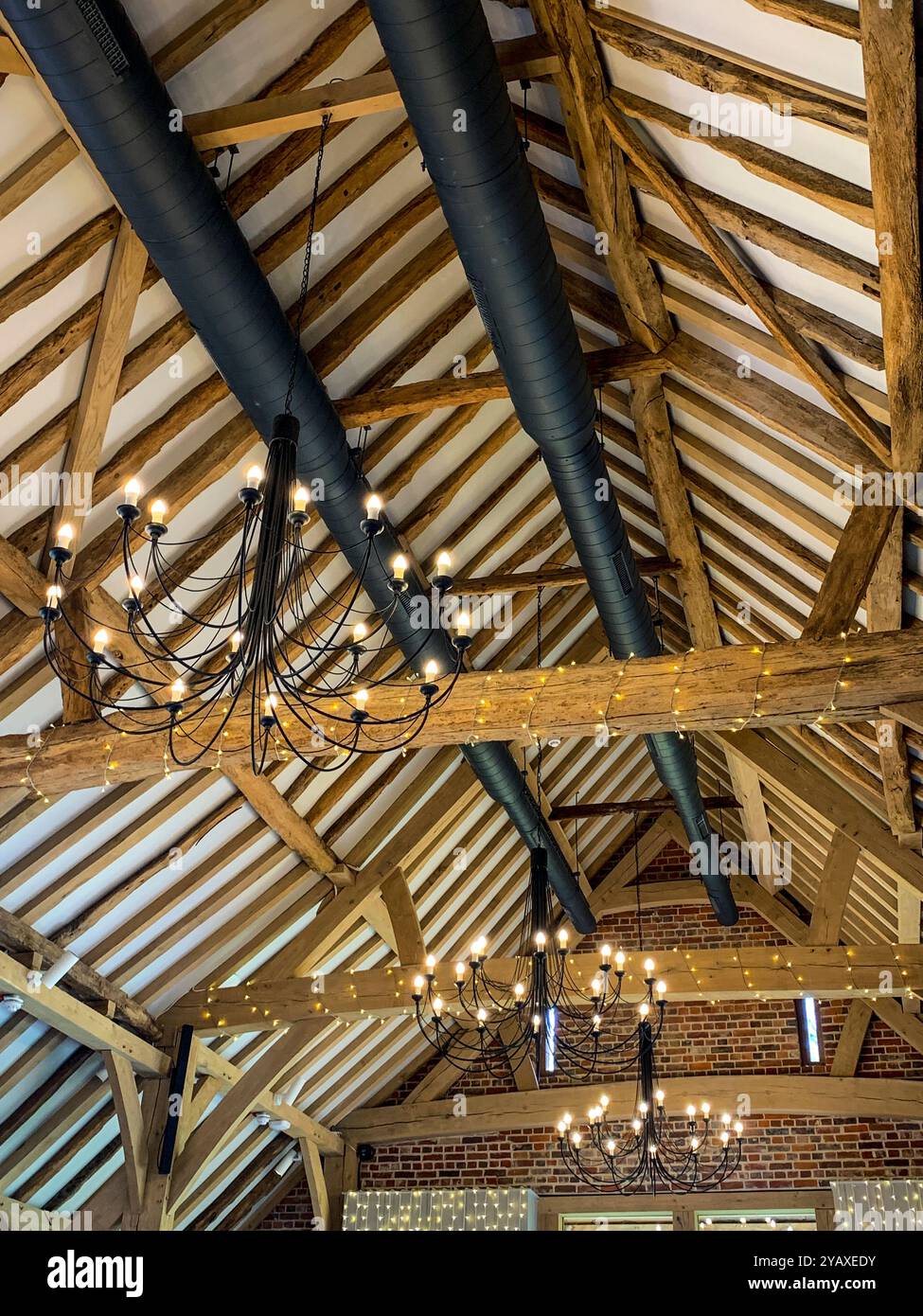 Looking up at the massive restored interior timber roof construction in a large old barn. A mobile phone photo with some phone or tablet post processing. - Smartphone Captured Stock Image