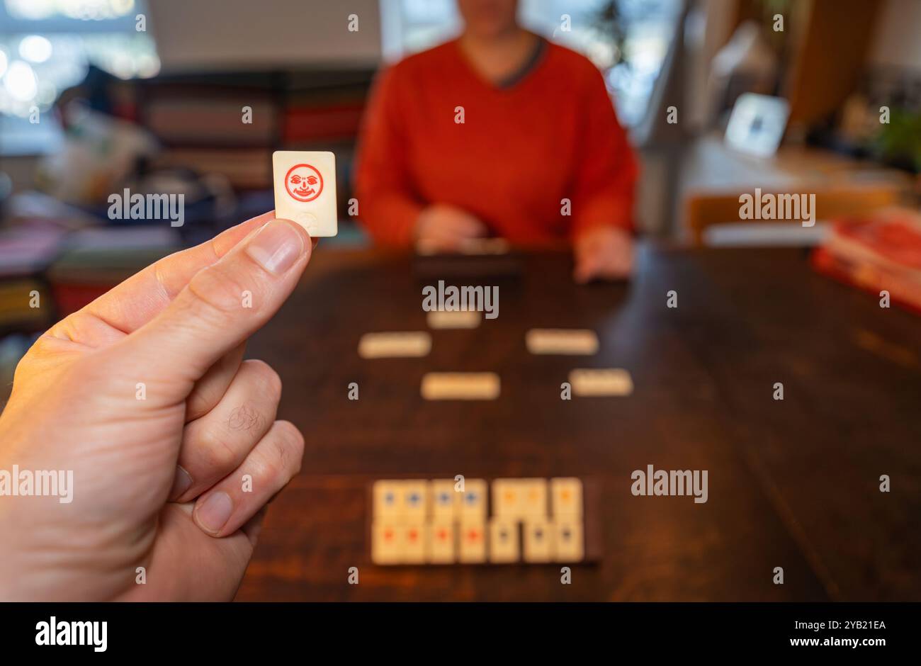 Playing classical board game rummikub at home, hand holding a joker tile Stock Photo