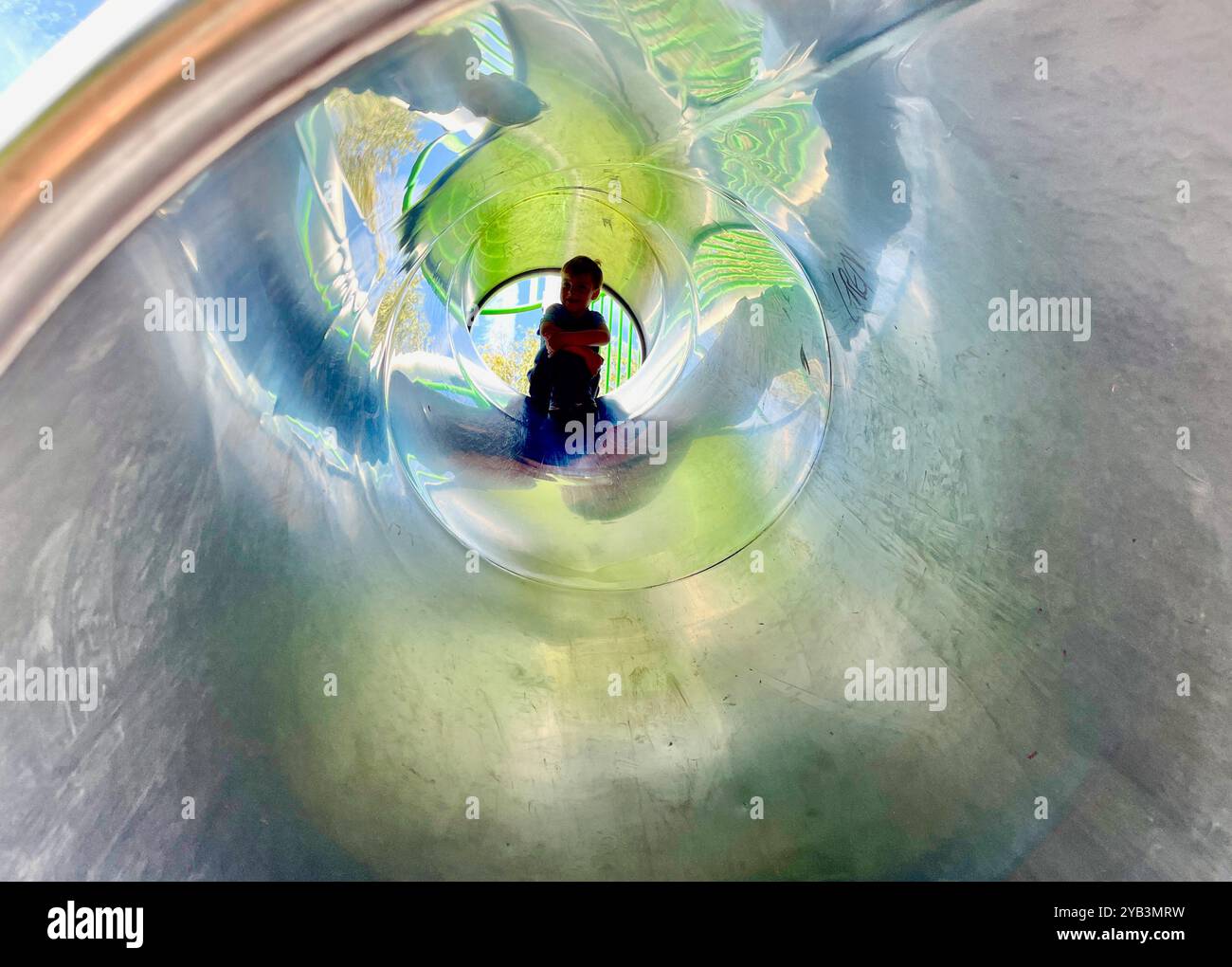 Small boy  on a metal slide in children’s playground - Smartphone Captured Stock Image