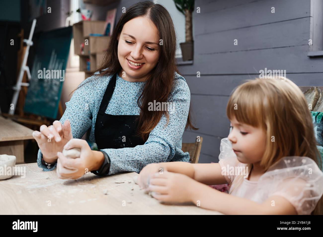 A woman and a child create pottery in a cozy studio during the ...