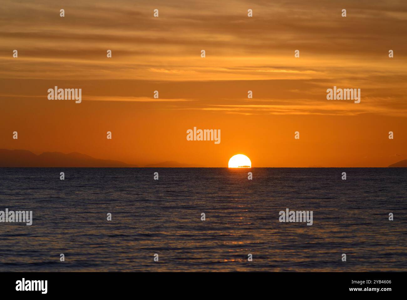 Serene Sunset Over Calm Ocean Horizon and Golden Sky, Tuscany, Italy Stock Photo