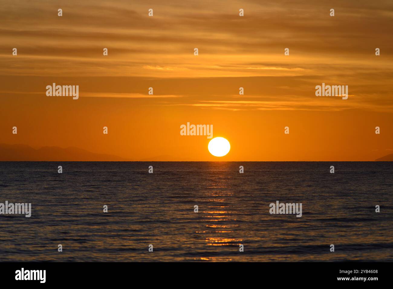 Serene Sunset Over Calm Ocean Horizon and Golden Sky, Tuscany, Italy Stock Photo