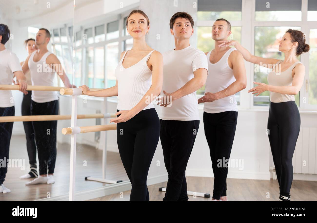 Group practicing ballet positions at barre with female instructor Stock Photo