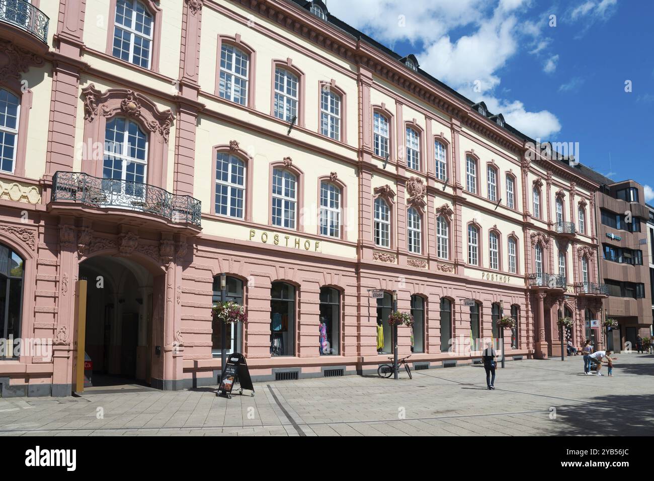Historic building in pink and beige in the city centre with pedestrians under a blue sky, Posthof am Kornmarkt, former post office building, Trier, Rh Stock Photo