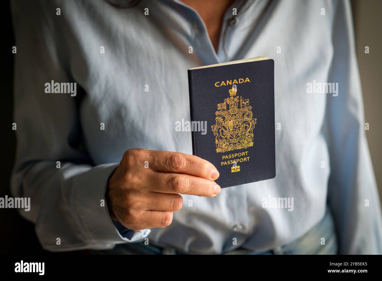 Woman is holding a Canadian passport in her hand, ready to embark on an international journey Stock Photo