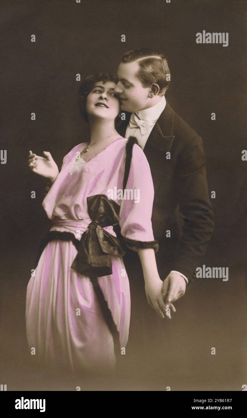 Vintage hand-coloured photograph of a romantic couple embracing. Adapted from an old postcard. Stock Photo