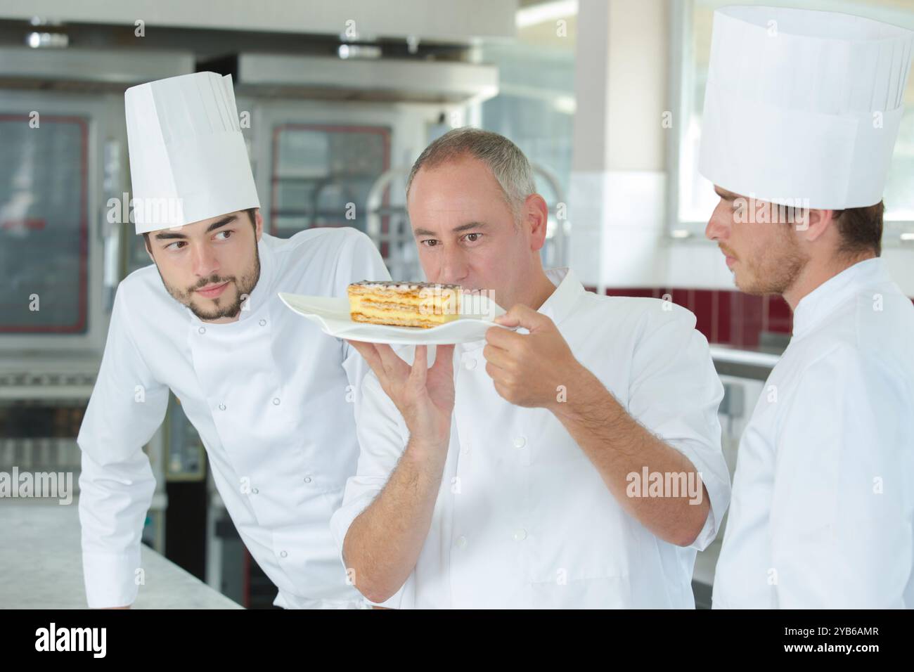 apprentices looking at chef during work in the kitchen Stock Photo
