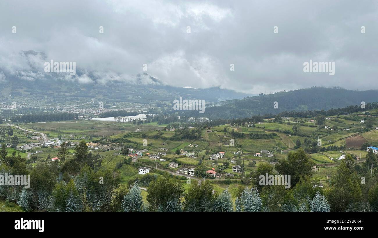 Landscape view between Quito and Ibarra in Ecuador, clouds touching the hilltops due to the altitude, lush green fields and small villages below Stock Photo