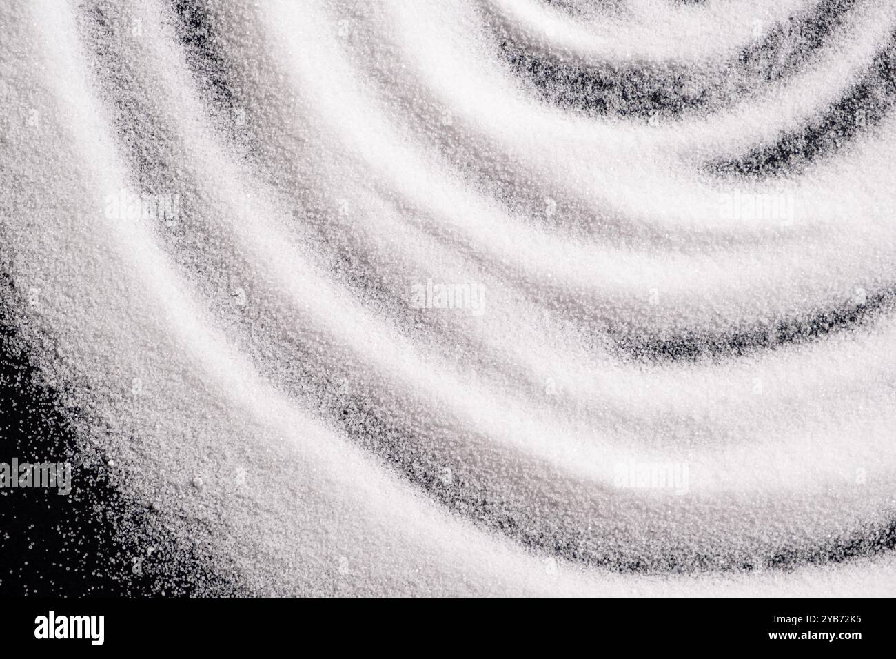 Finely ground stone white rock salt texture on black background, top view Stock Photo