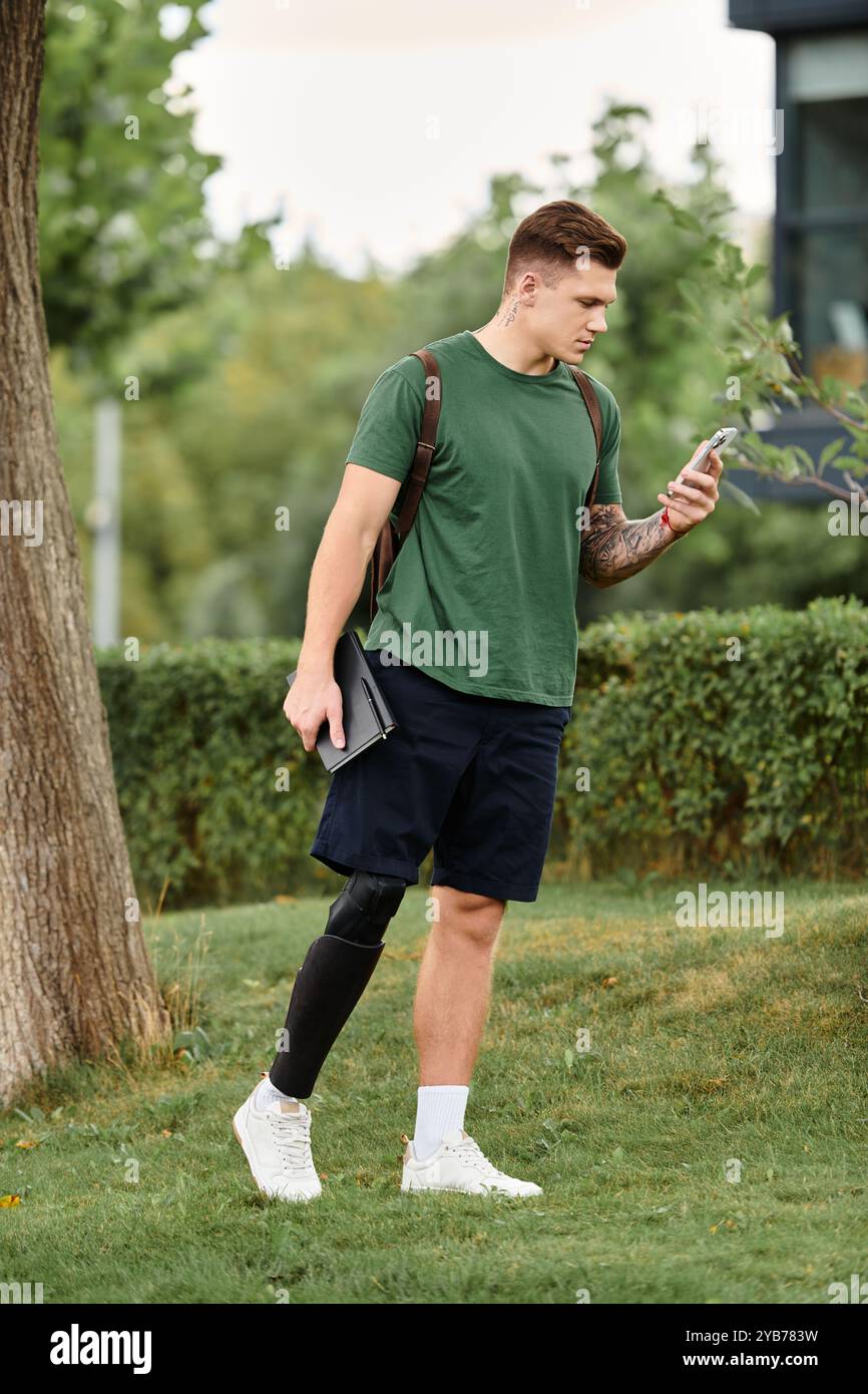 A young man steps confidently through a park, engaging with his phone ...