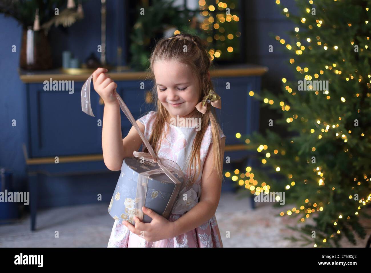 Child Eagerly Unwrapping A Gift In Front Of A Beautifully Decorated child-eagerly-unwrapping-a-gift-in-front-of-a-beautifully-decorated