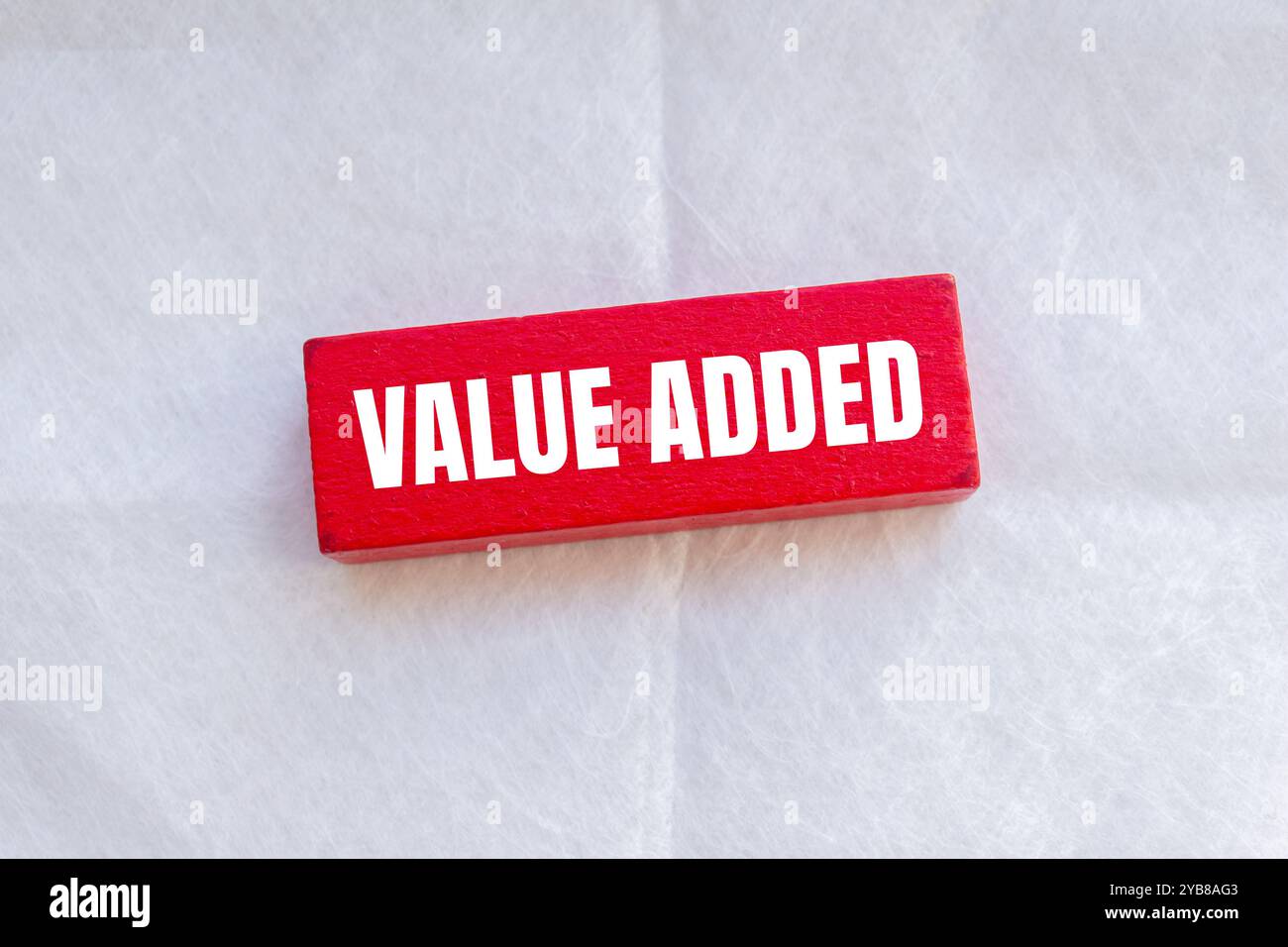 Value added message written on red wooden block with white background ...