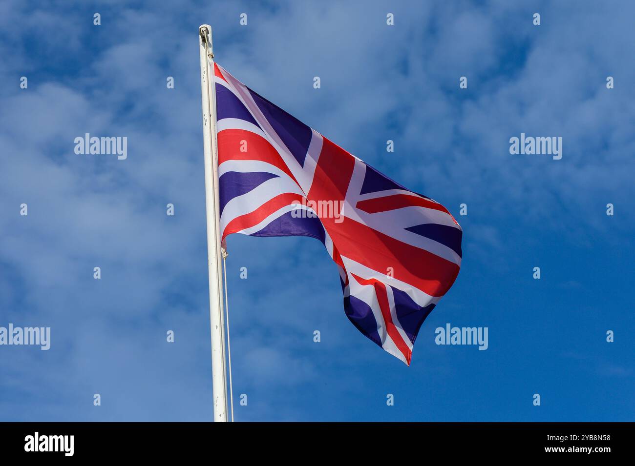 The Union Jack proudly flutters atop a flagpole against a backdrop of a ...