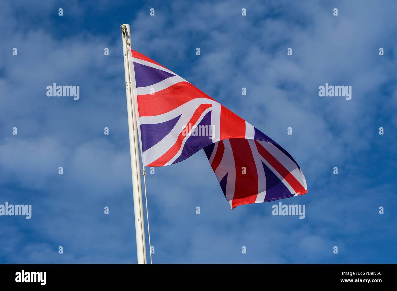 A vibrant Union Jack flag flutters in the breeze beneath a bright blue ...