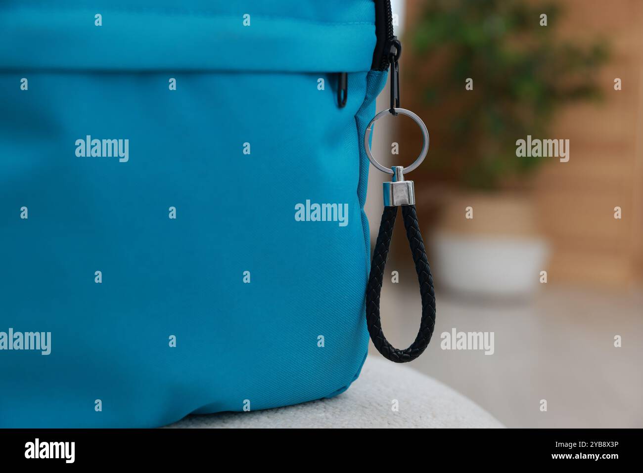 Backpack with black leather keychain on soft surface indoors, closeup. Space for text Stock Photo