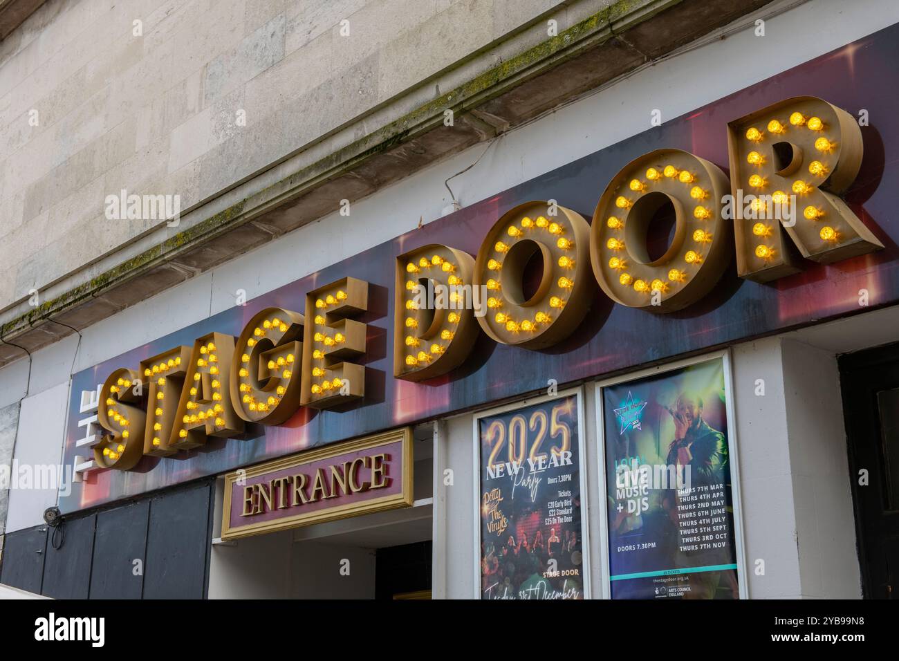large neon light illuminated stage door sign above a theatre entrance ...