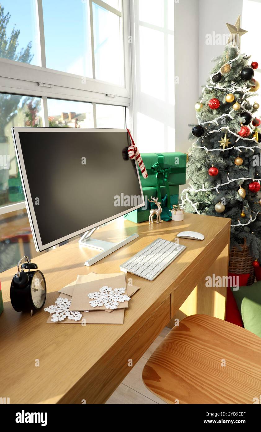 Workplace with computer monitor, presents and Christmas tree in office ...