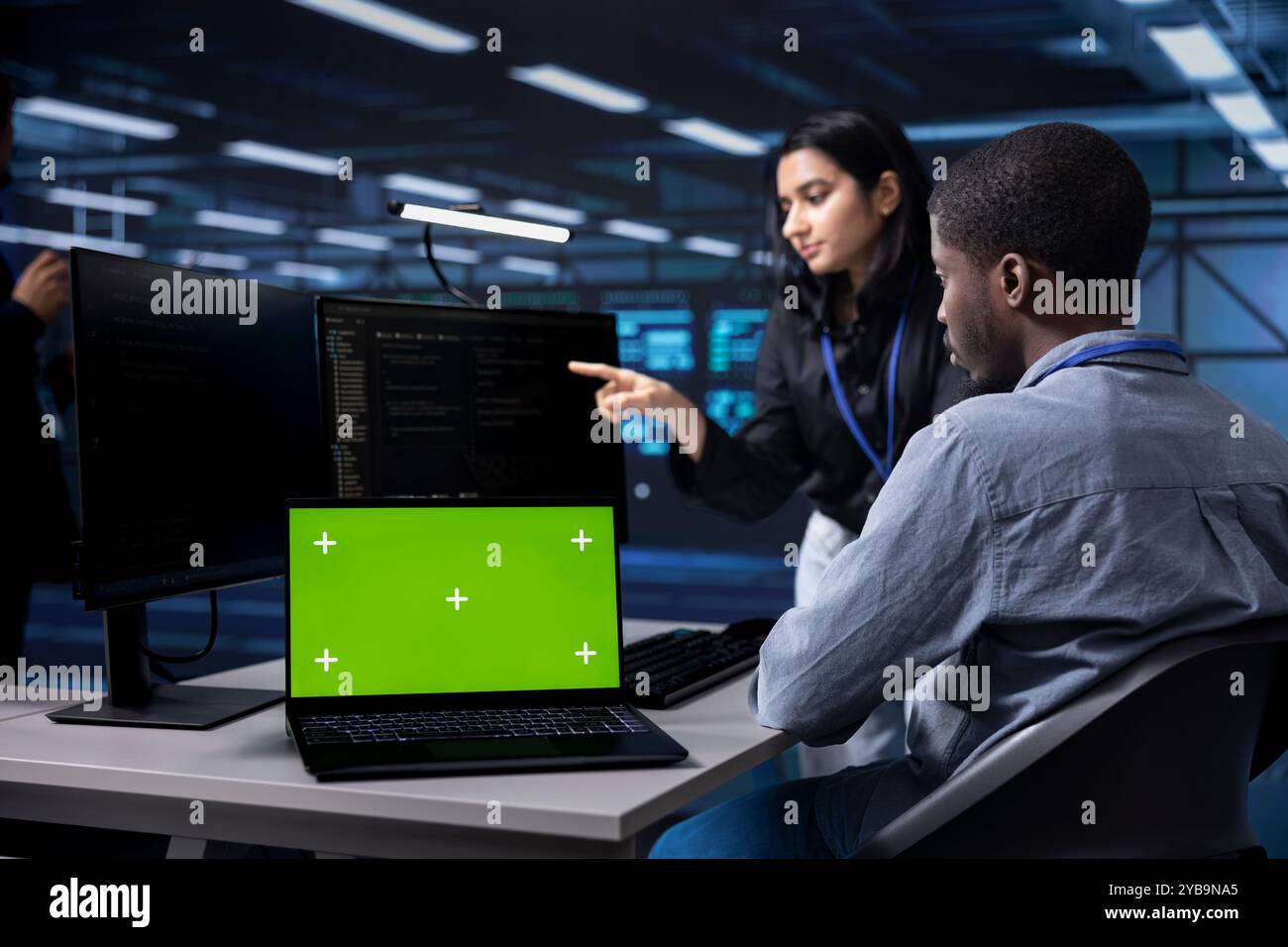 Admins using mockup laptop to reconfigure server room facility, optimizing it for data processing requirements. Workers using green screen notebook, ensuring data center tech operates efficiently Stock Photo