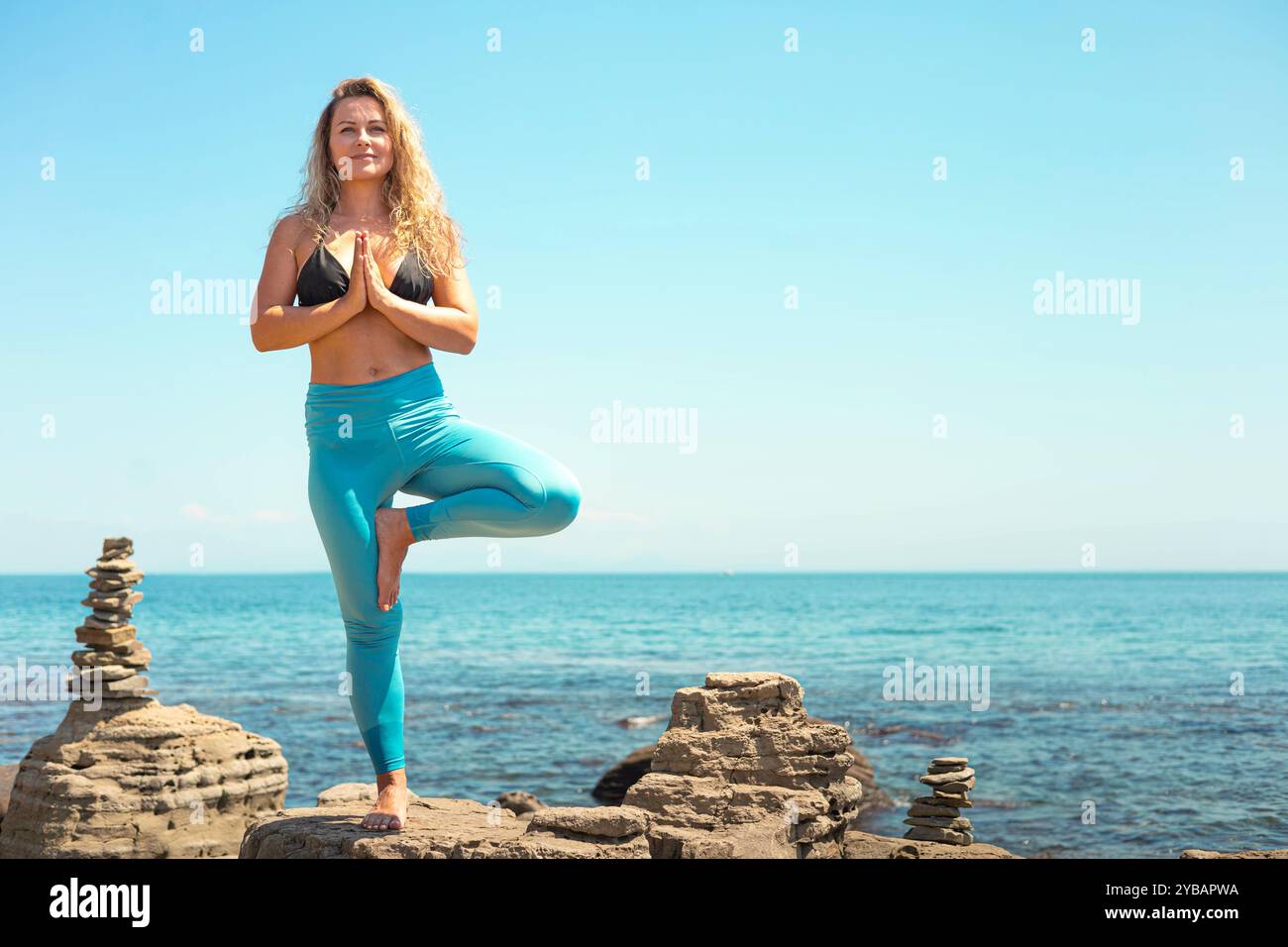 Yoga woman standing in vrikshasana tree pose hand namaste on cliff at ...