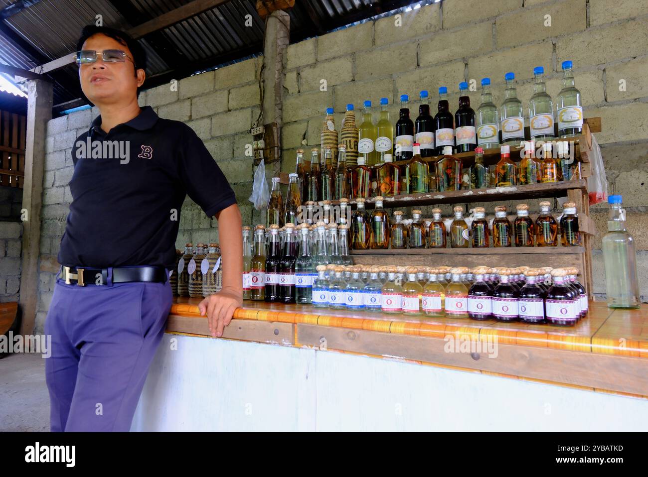 A male tour guide introduce distilled Laotian rice spirits in Ban Xang Hai village aka Whisky Village to visitors.near Luang Prabang, Laos Stock Photo