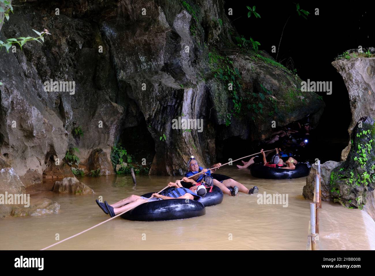 Tourists following a rope tubing into the Tham Nam Water Cave.Vang ...