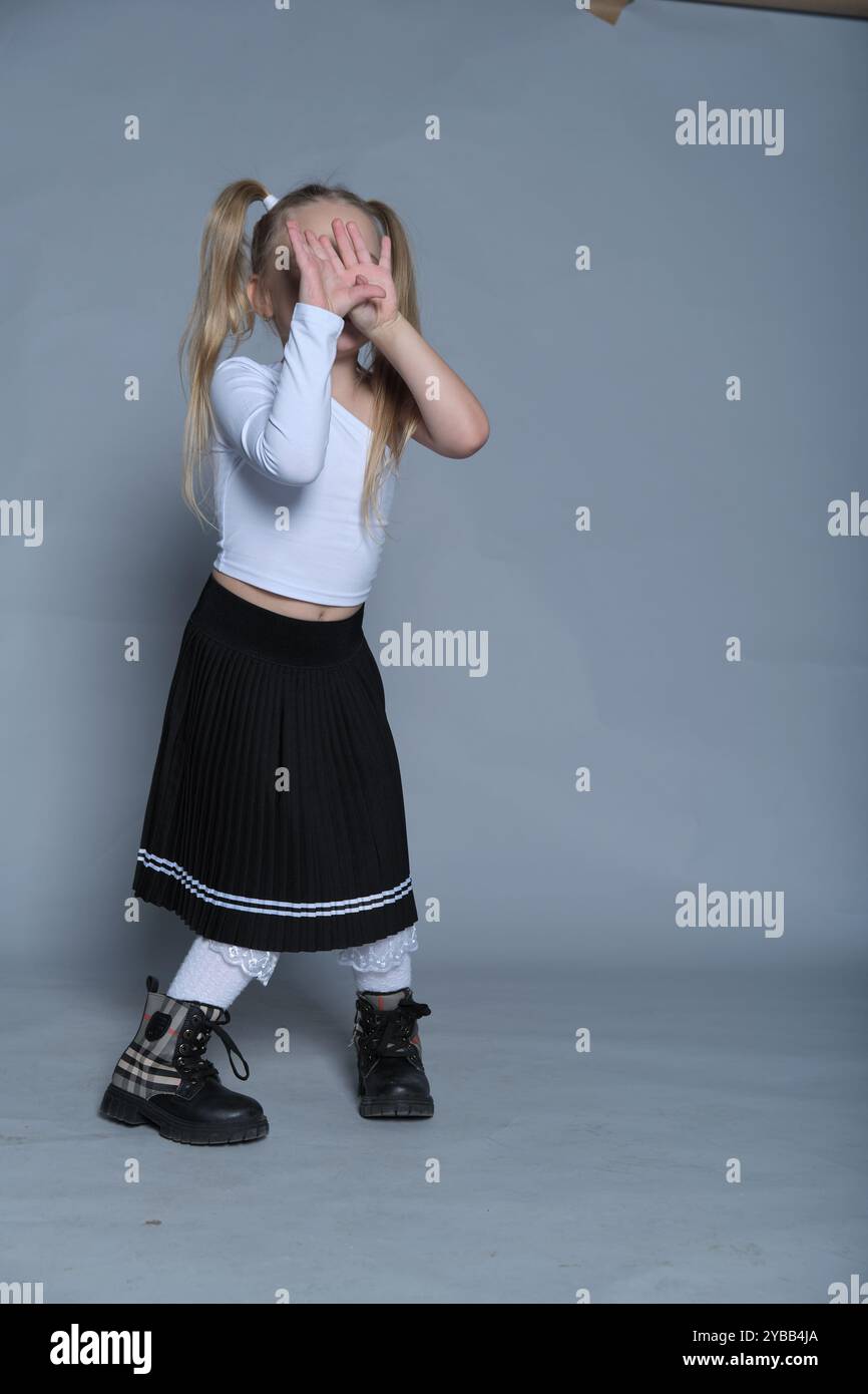 joyful little girl poses as if dancing, her arms raised playfully in a ...