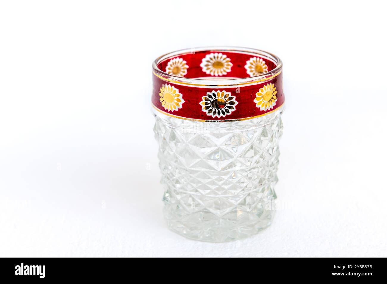 A vintage crystal glass cup with decorated rim, isolated on a white background. Stock Photo