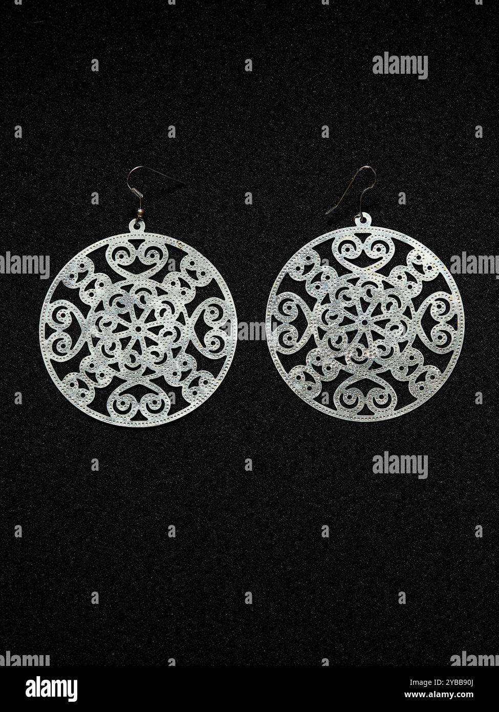Round metal earrings on black textile background Stock Photo