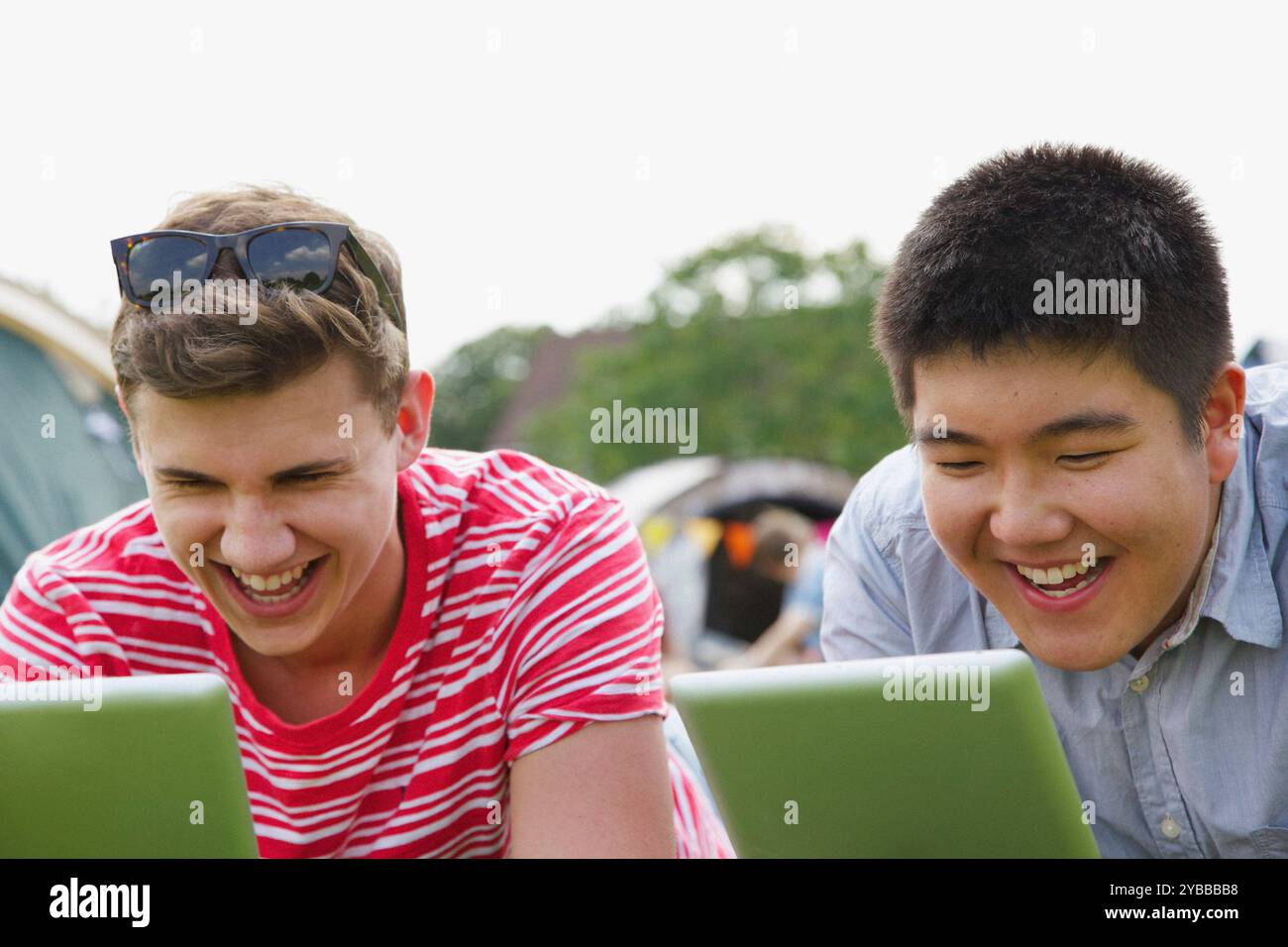 Laughing Teenage Boys Using Tablets Stock Photo