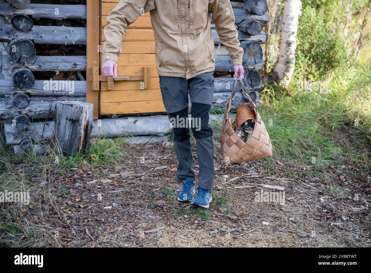 Man with firewood in basket Stock Photo