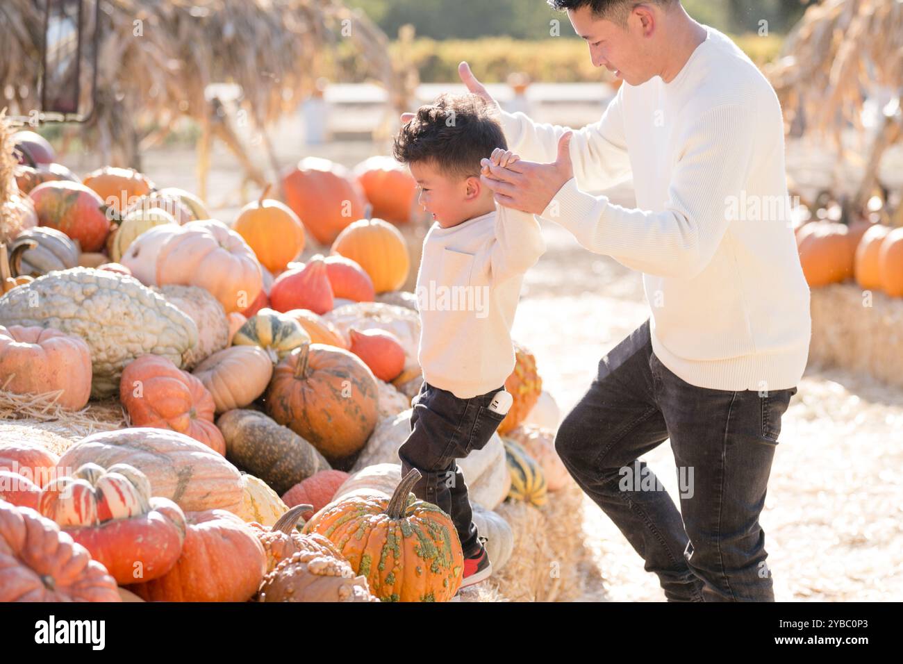 Father and son climbing through hay and pumpkins Stock Photo