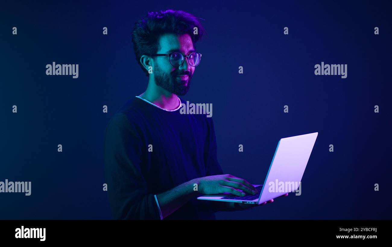 Arabian Indian man guy male programmer coder employer freelancer working using internet computer developer businessman business guy gamer hold laptop Stock Photo
