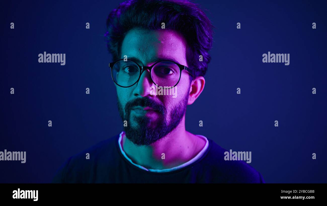 Close up portrait neon ultraviolet background Indian man guy developer coder smart hacker clever coding computer engineer showing gesture think about Stock Photo