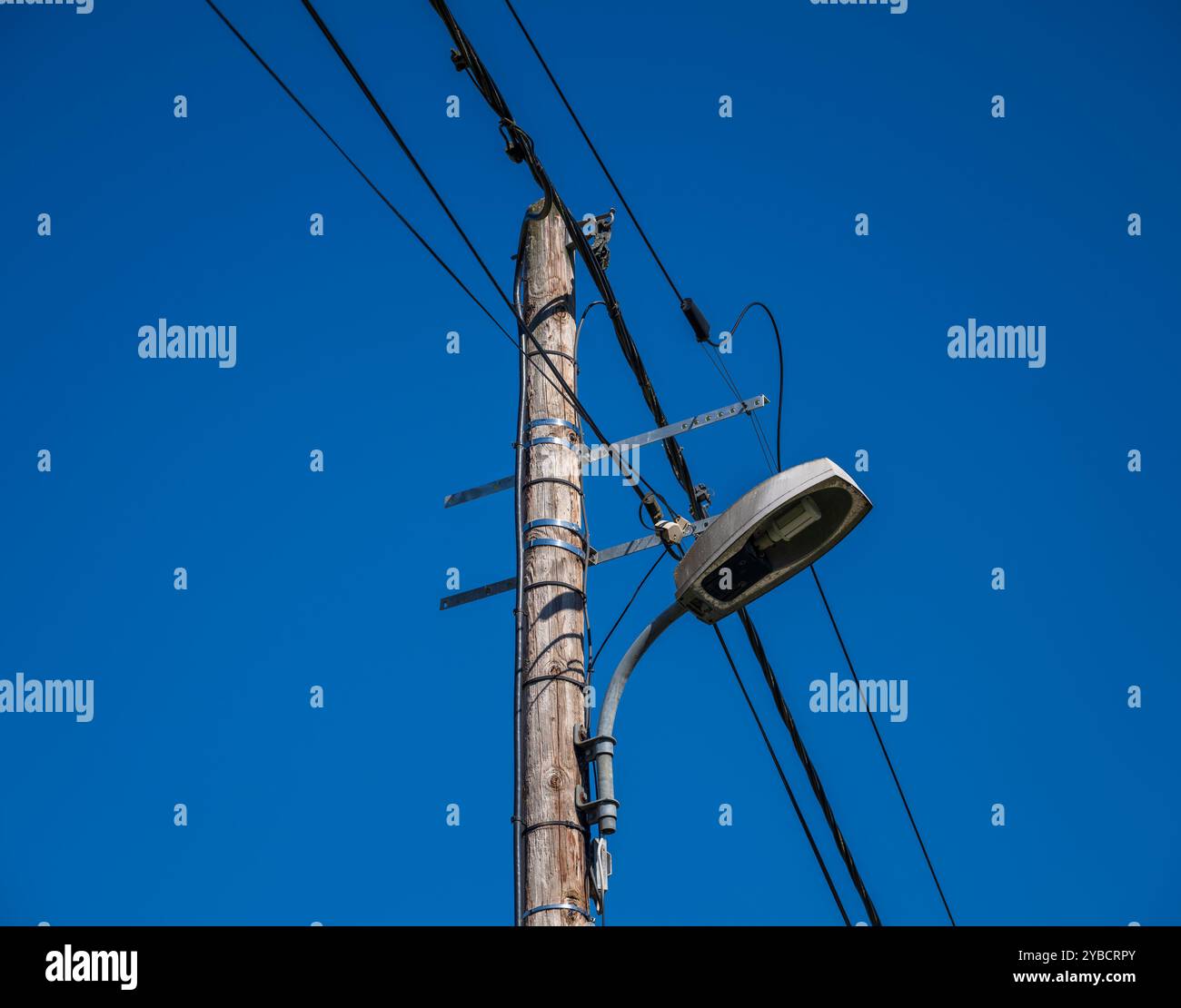 Telegraph pole supporting power lines and street lamp, France. Stock Photo
