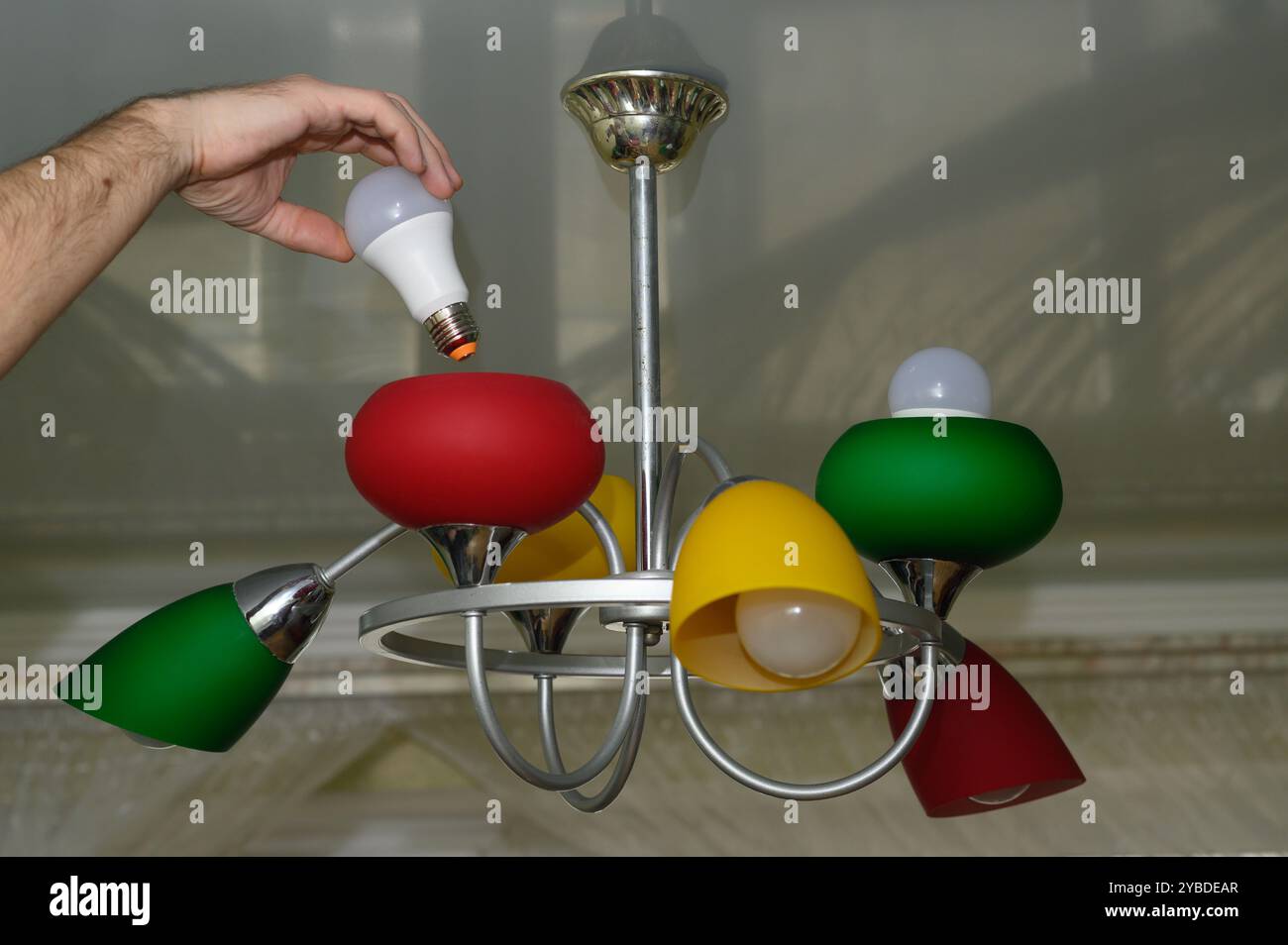 replacing the light bulb in the chandelier. LED lamp. Stock Photo