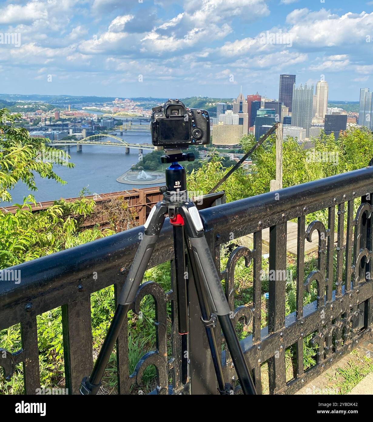 Pittsburgh, Pennsylvania, USA - 27 August 2023: A camera mounted on a tripod captures the vibrant skyline of Pittsburgh with rivers below on a bright Stock Photo