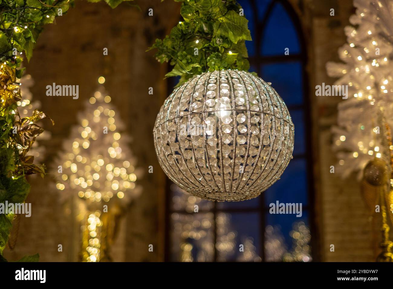A stunning crystal chandelier illuminates a festively adorned hall with ...