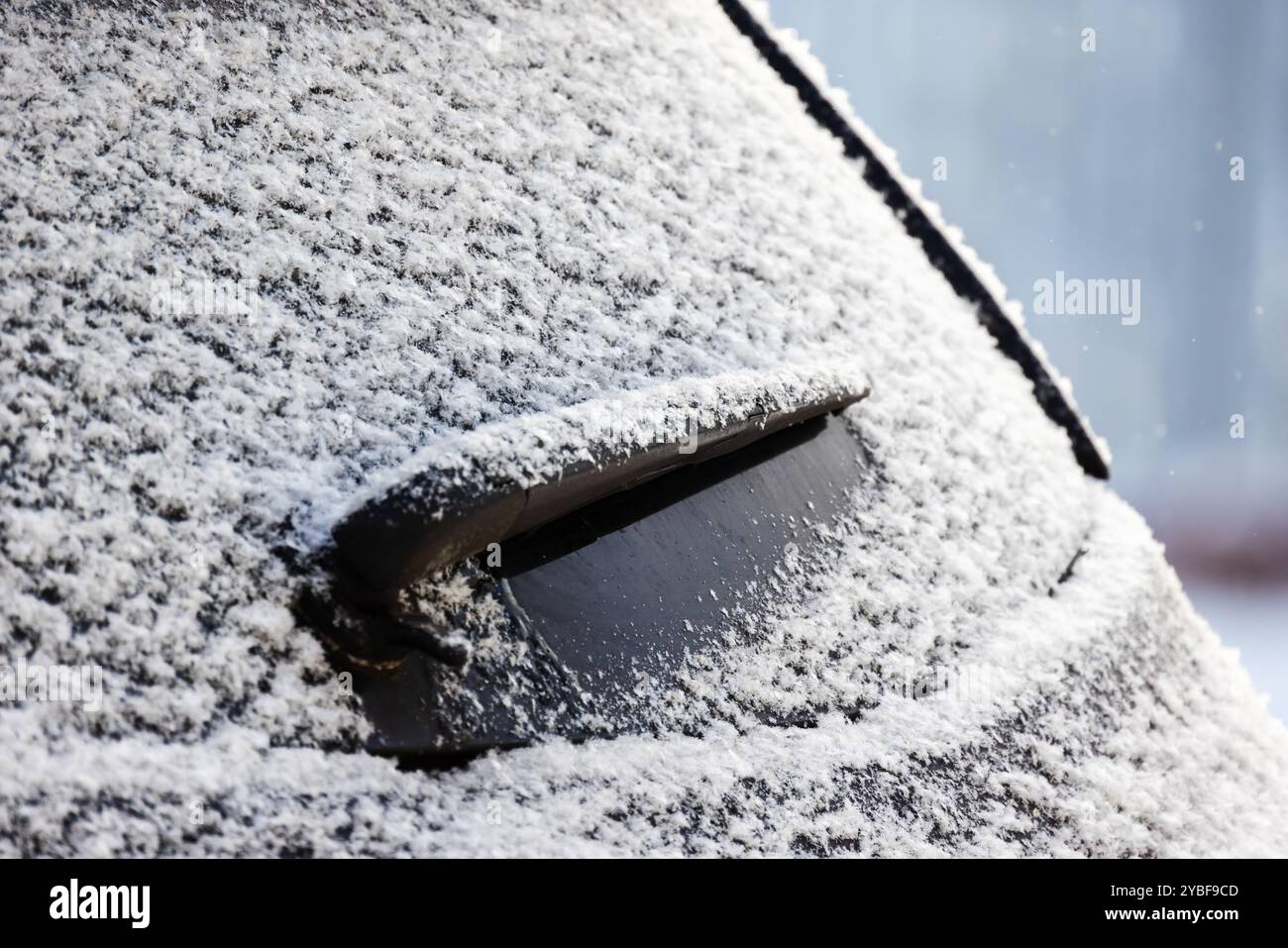 Close-up photo of a car wiper on rear window of modern SUV car covered with snow Stock Photo