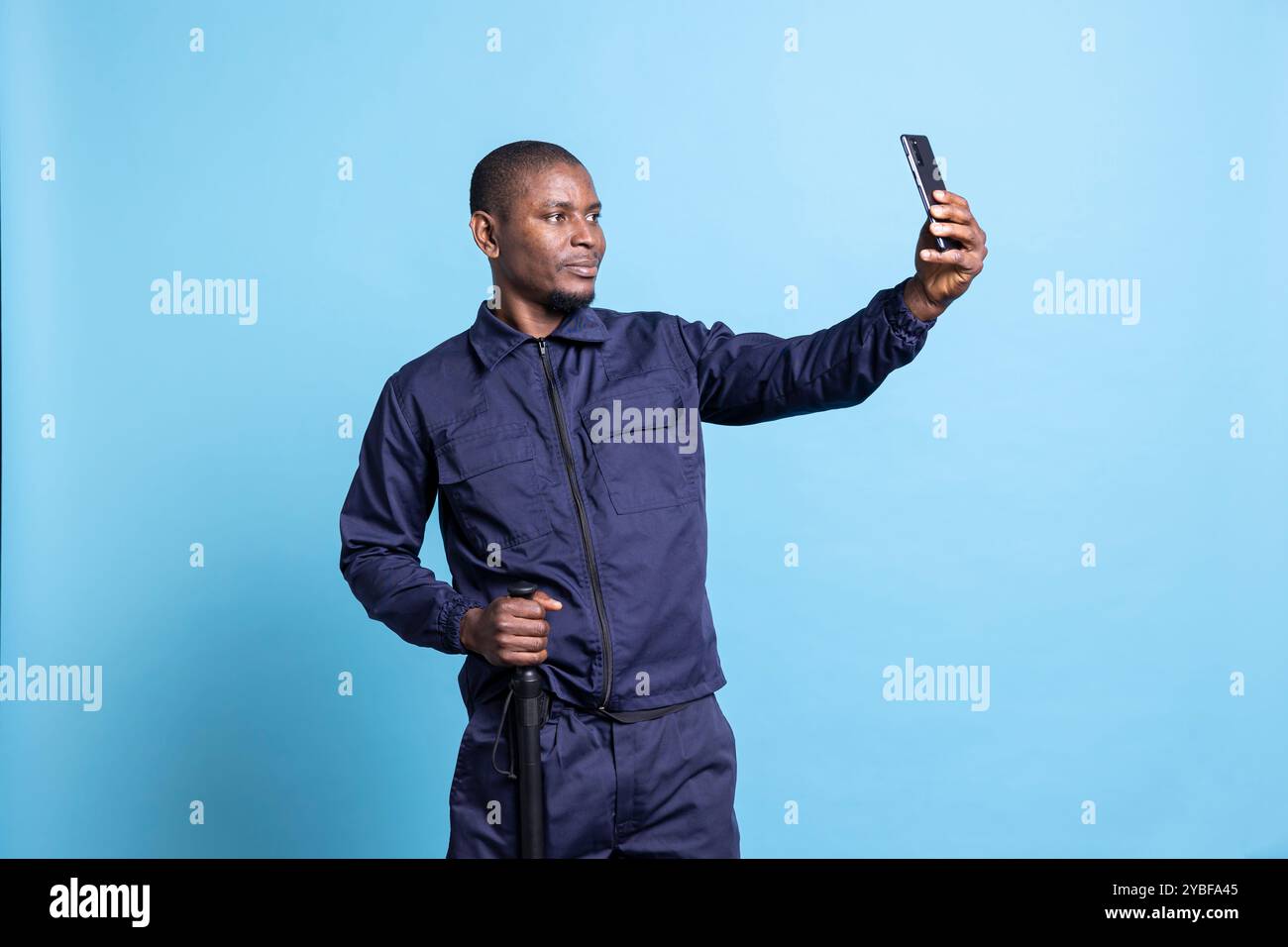Proud security guard taking pictures with his baton in studio, using a ...
