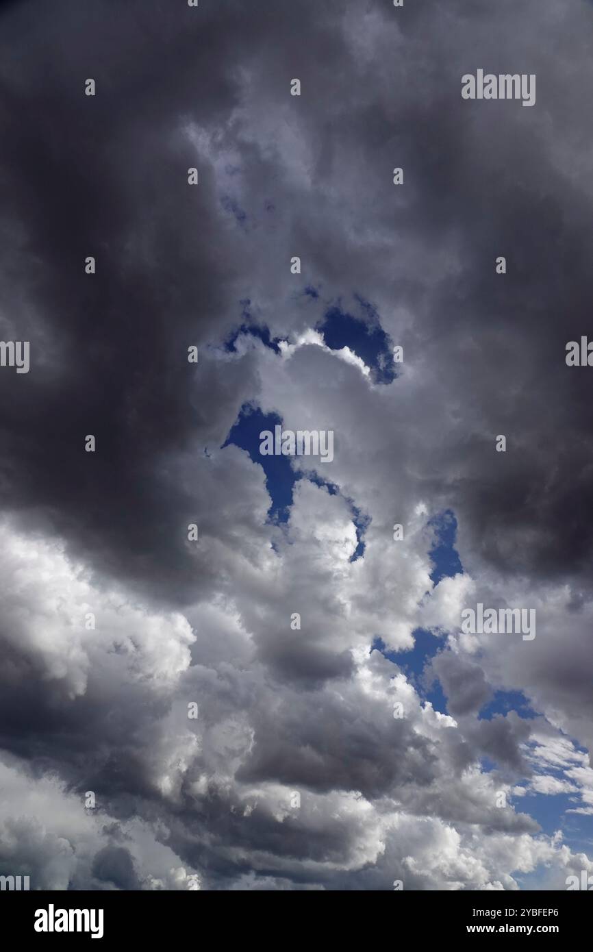 Gathering storm clouds loom overhead, filled with varying shades of gray and white, revealing patches of blue sky during the afternoon hours, suggesti Stock Photo