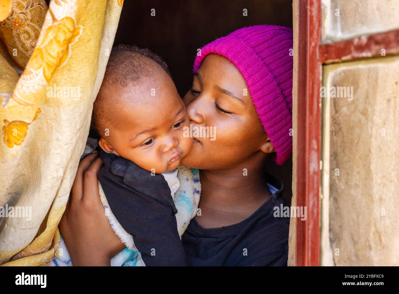 village happy african mother kissing her baby at the window Stock Photo