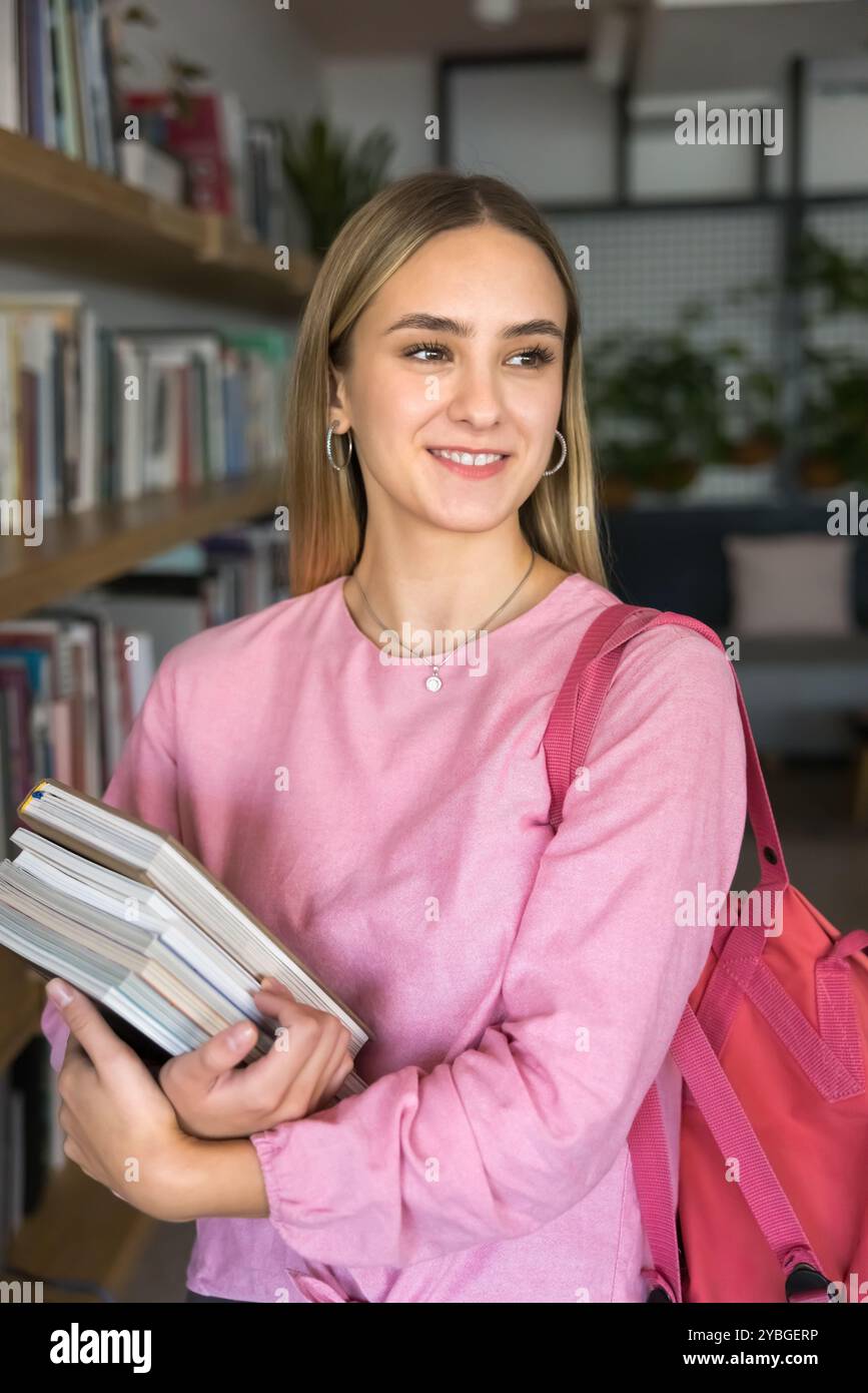 Happy young student girl holding stack of textbooks Stock Photo - Alamy