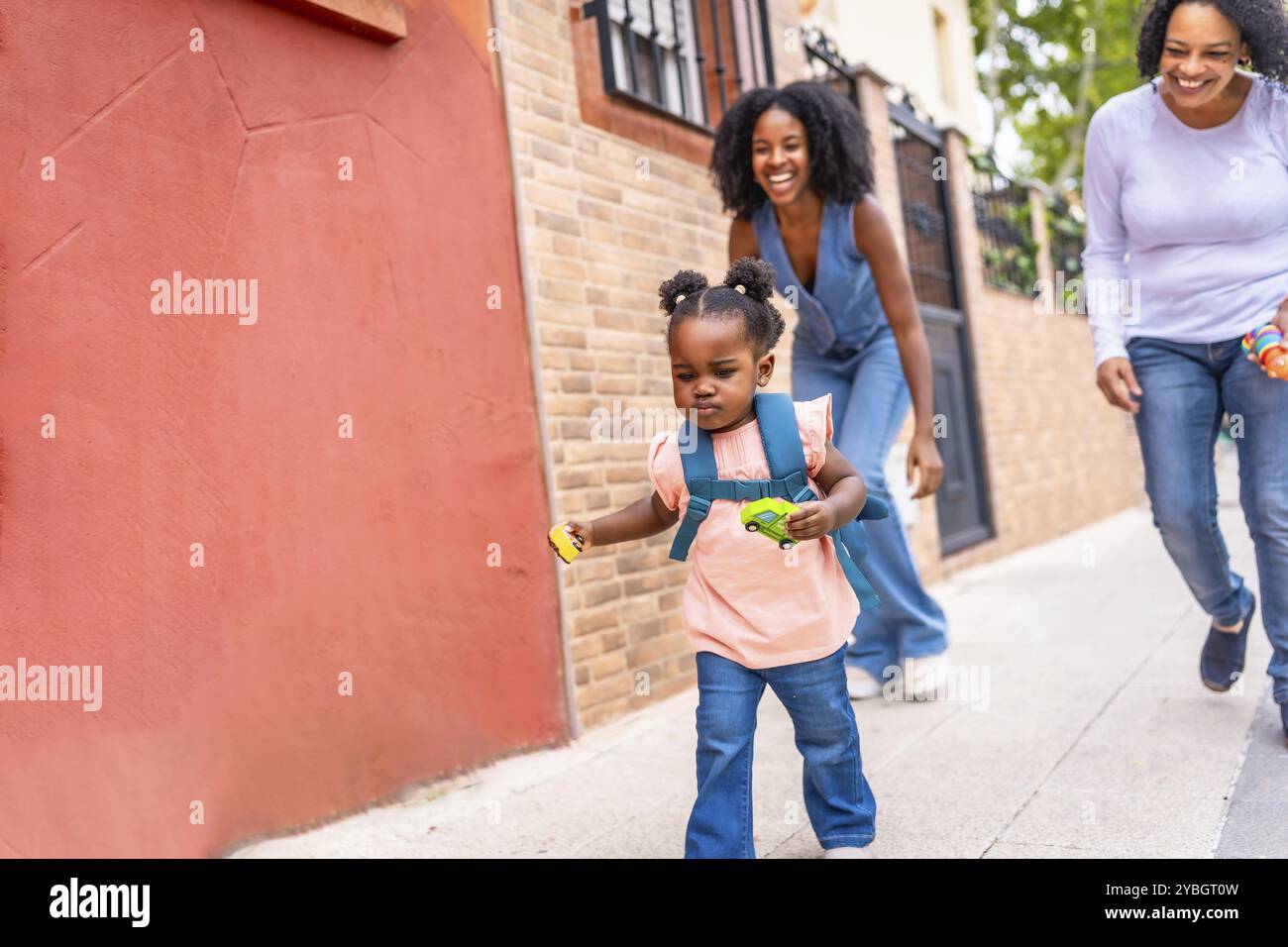 African mother and grandmother running along street chasing a playful girl Stock Photo