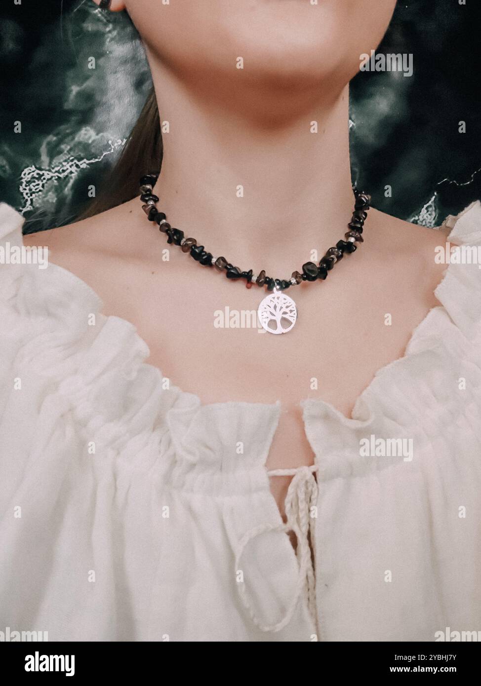 Black obsidian choker with tree of life pendant on woman's neck - Smartphone Captured Stock Image