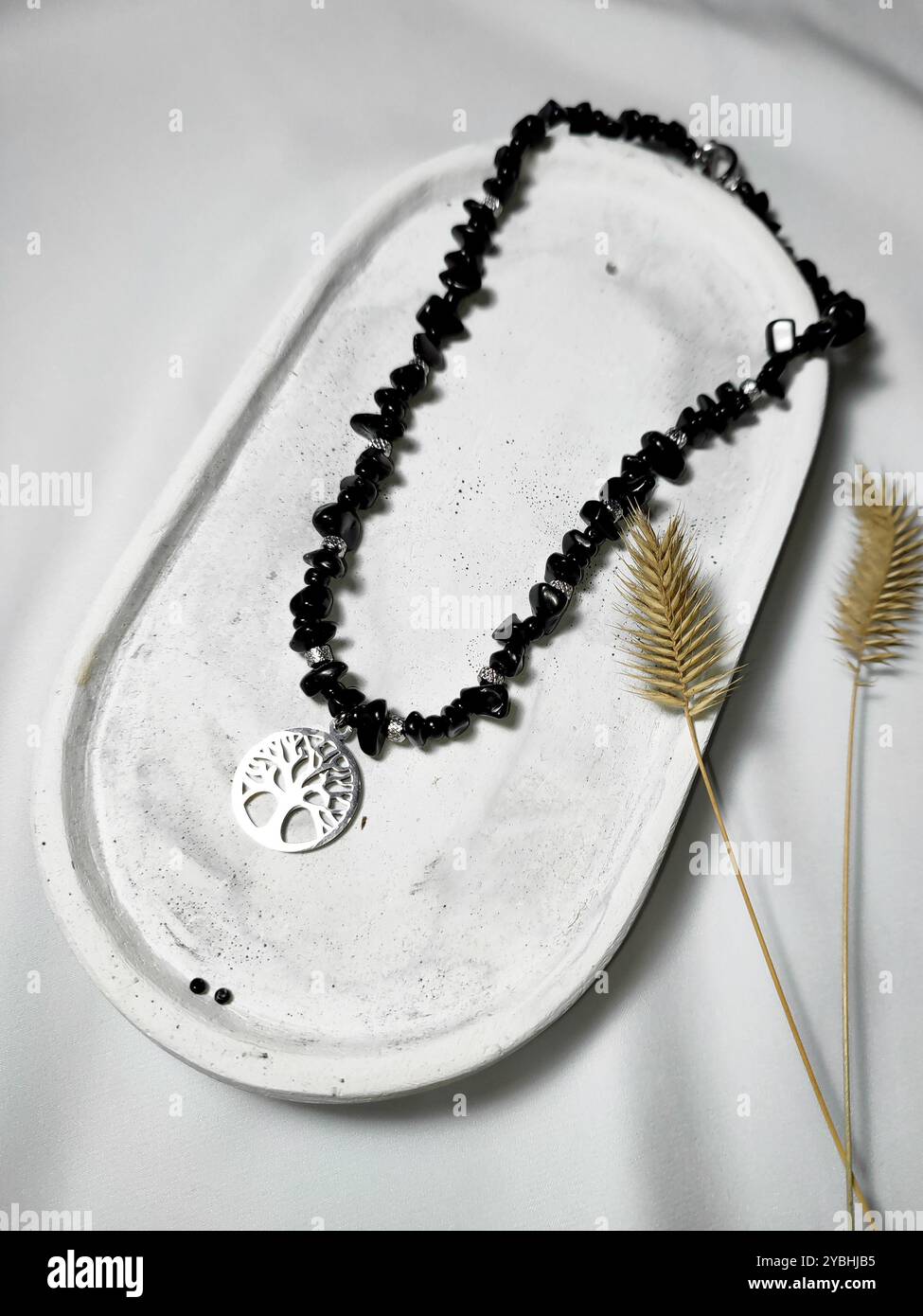 Black agate gemstone necklace with tree of life charm at white background. Female accessory, woman's fashion. Natural stone jewelry flat lay, beaded - Smartphone Captured Stock Image